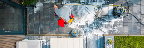 Photo from above looking down on caretaker cleaning back porch with special cleaning equipment.