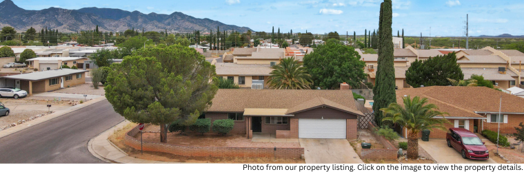 Drone view of home in a neighborhood with mountains in the background.