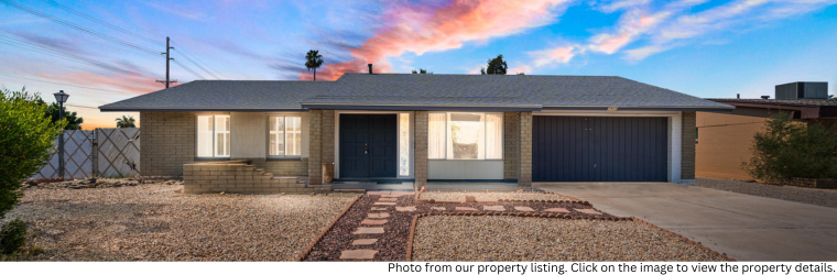 Twilight style photo of the front of a house with decorative gravel yard and a beautiful sunset sky.